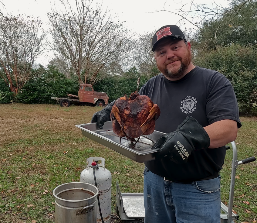 Deep fried turkey with crispy golden skin resting on a rack before carving