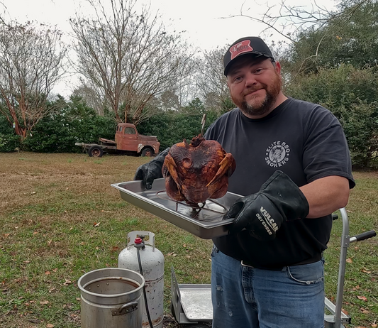 Deep fried turkey with crispy golden skin resting on a rack before carving